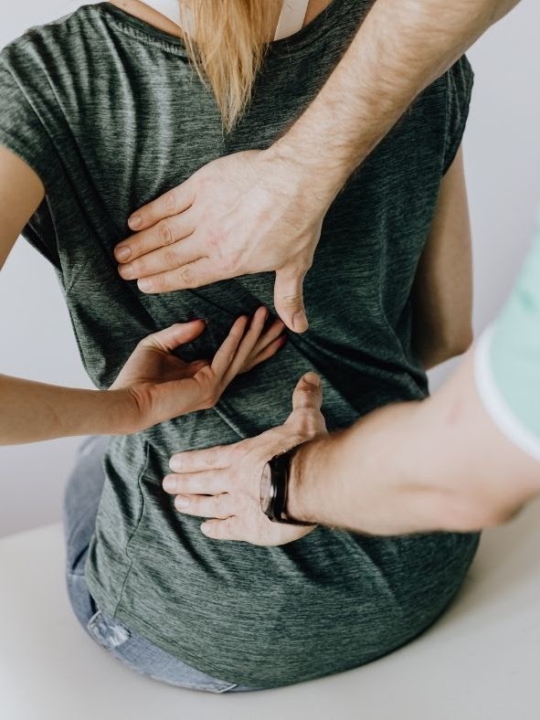 A chiropractor helps a patient with chiropractic care by making an adjustment along her spinal column.