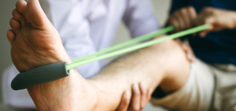 A person does a resistance bar workout as part of corrective exercise. They are stretching that leg out.